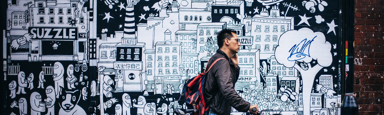 homme marchant avec son vélo, il téléphone. En arrière plan, fresque murale évoquant l’écosystème saturé de la ville.