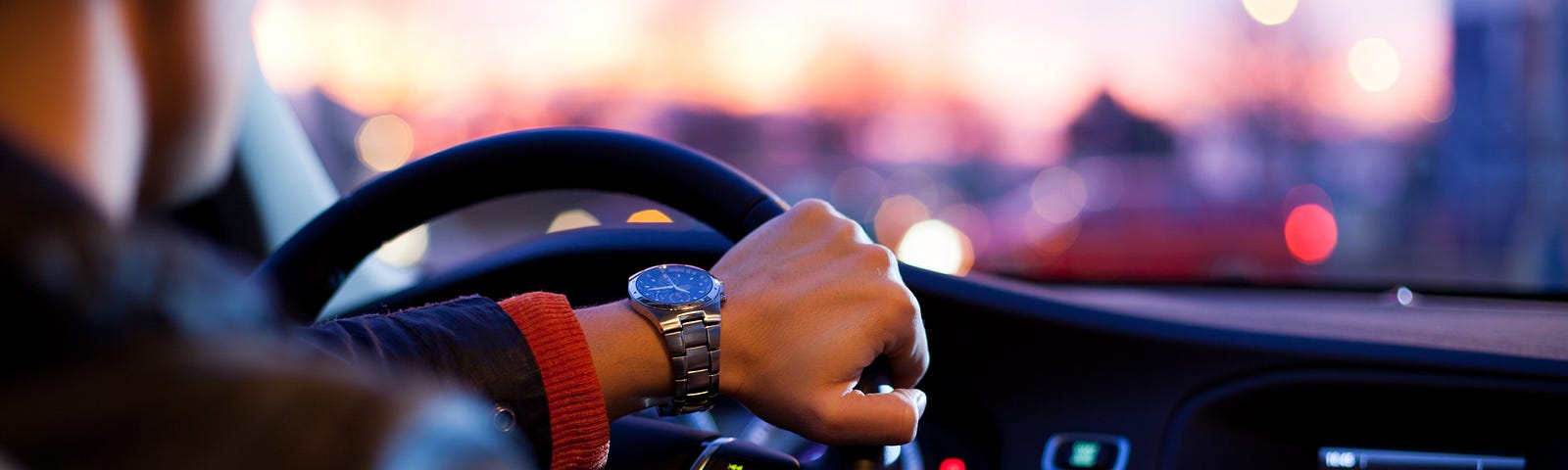man driving. Photo shows him sitting in car with hand on steering wheel.