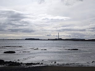 A grey landscape with the towers and buildings of Tiwai Point aluminium smelter visible in the distance