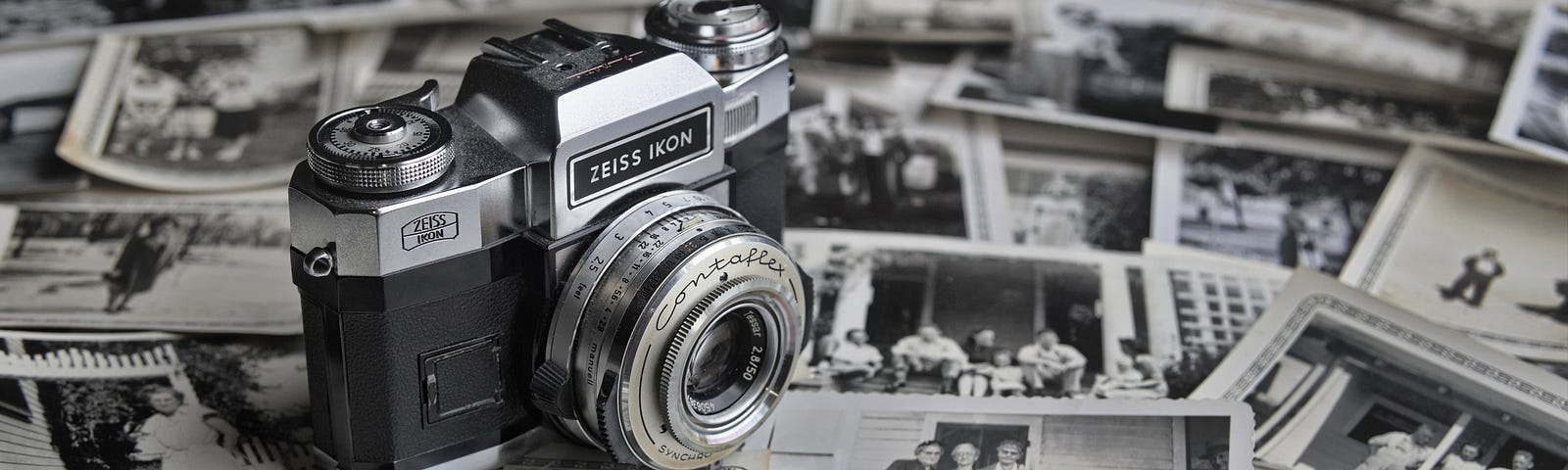 An old photo of a camera on top of a sea of old black and white photos.