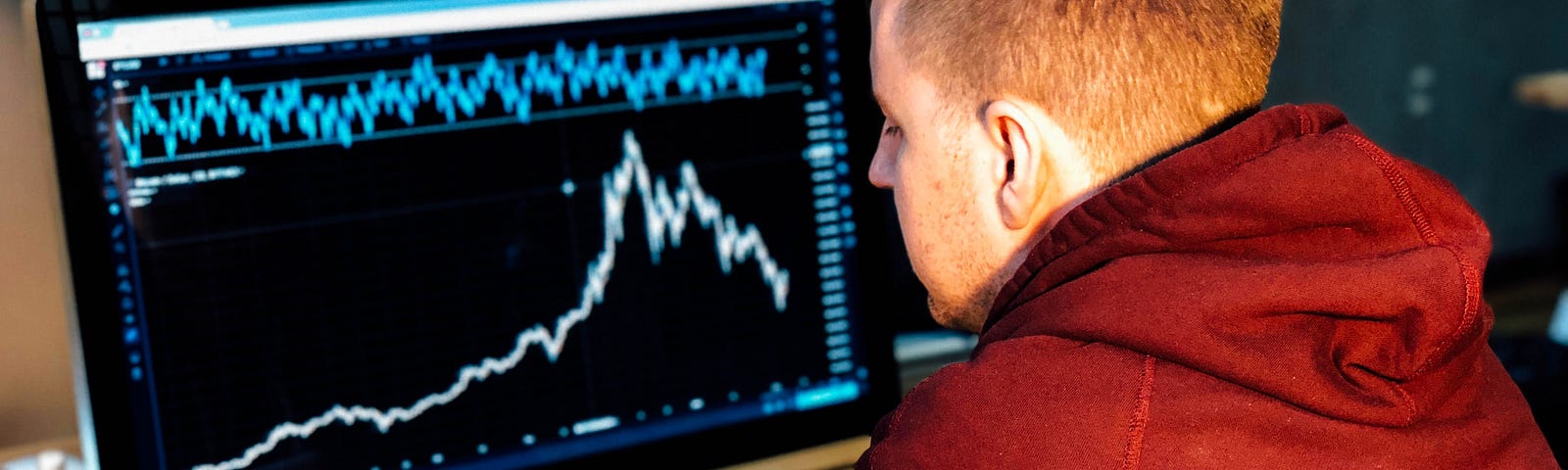 A man who’s using his phone in front a screen with graphs and statistics.