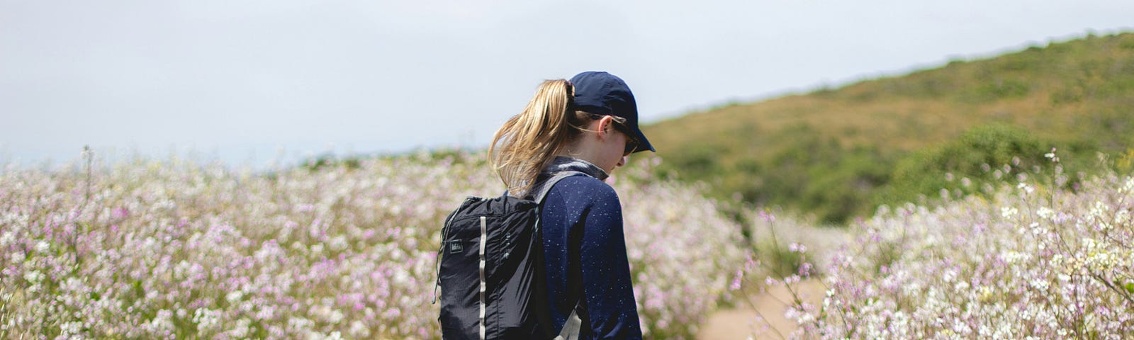 A woman walking along a path surrounded by flowers.
