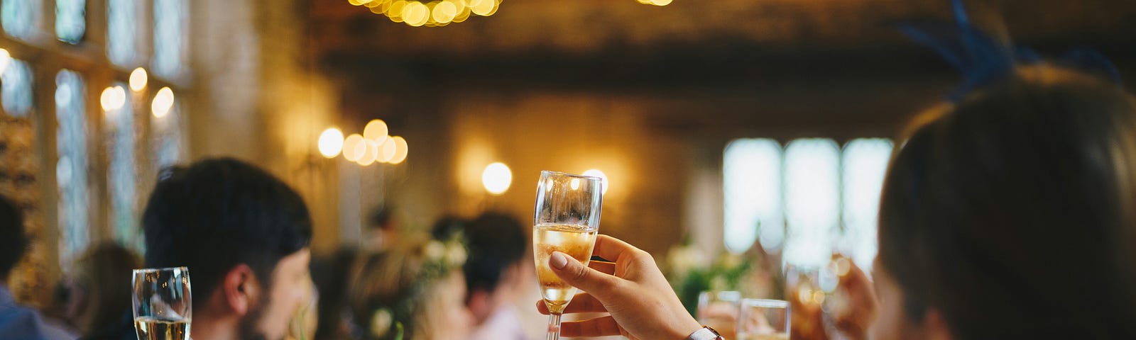 Image of people sitting at a formal table raising champagne glasses in a toast