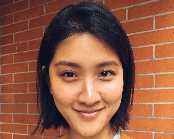 Headshot photo of a smiling Yehsong Kim wearing a light top with caramel-colored sweater