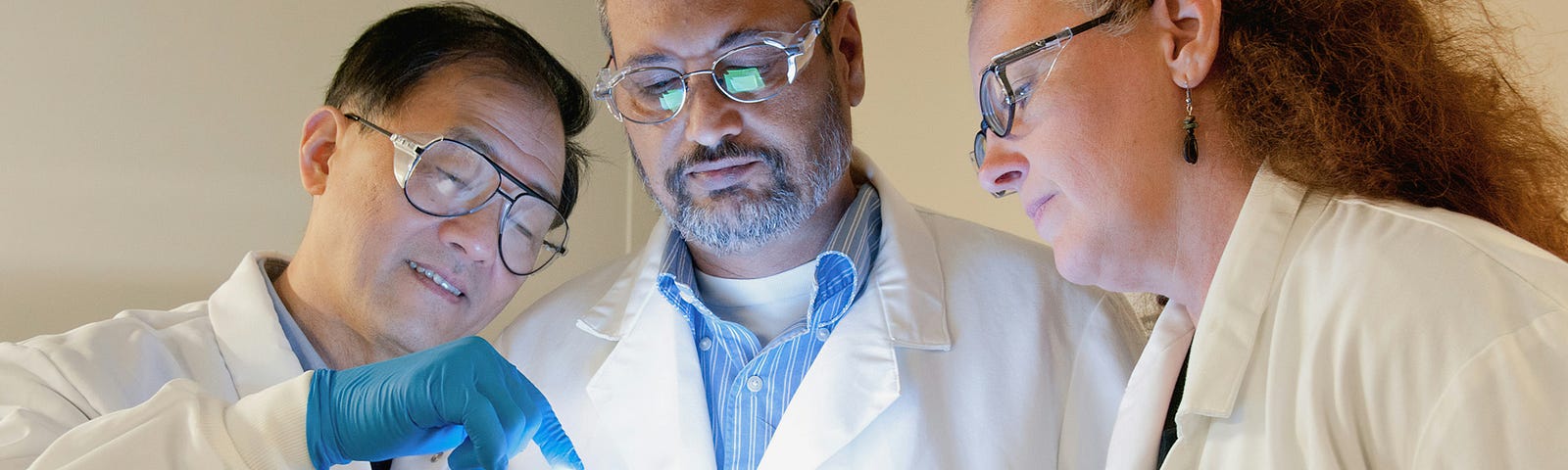 Three scientist looking at a small comouter screen.