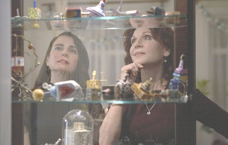 Ruth Berman (Marilu Henner) shows Christina (Mia Kirshner) her dreidel collection.