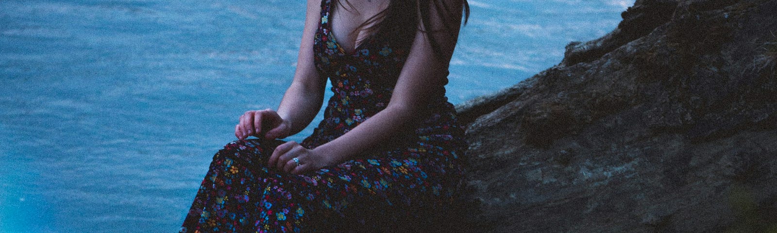 A woman sitting on a river-bank.