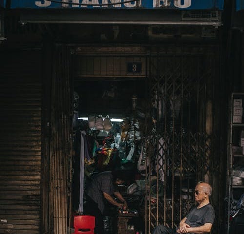 A shop keeper sits outside his ramshackle store in SouthEast Asia