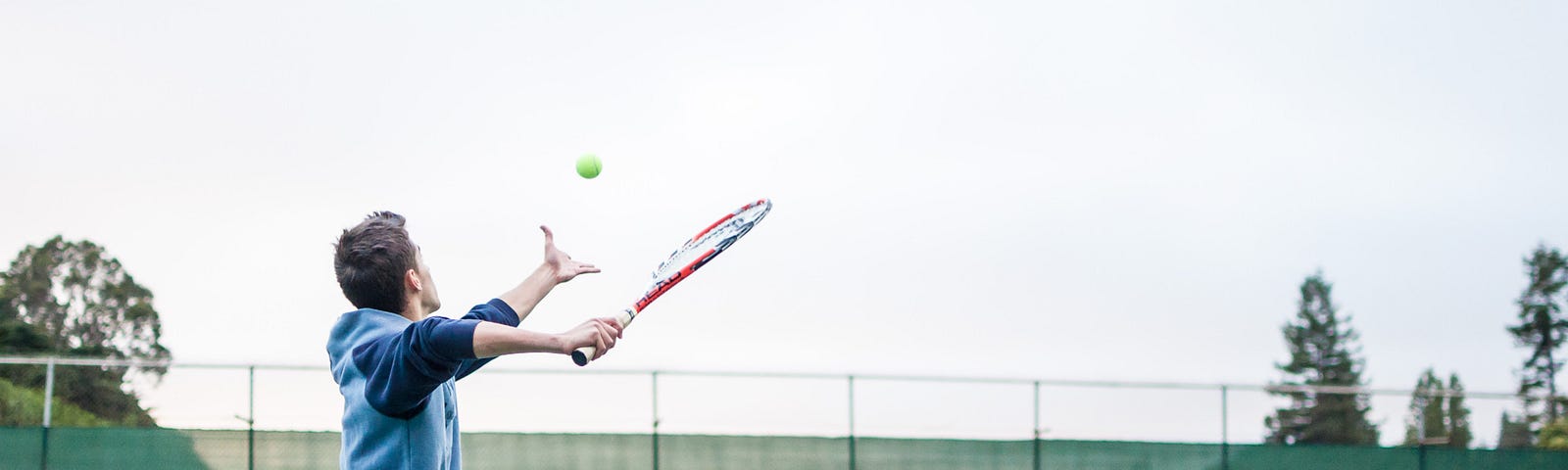 A tennis rookie incorrectly tosses the ball up. With consistency he can improve on his action