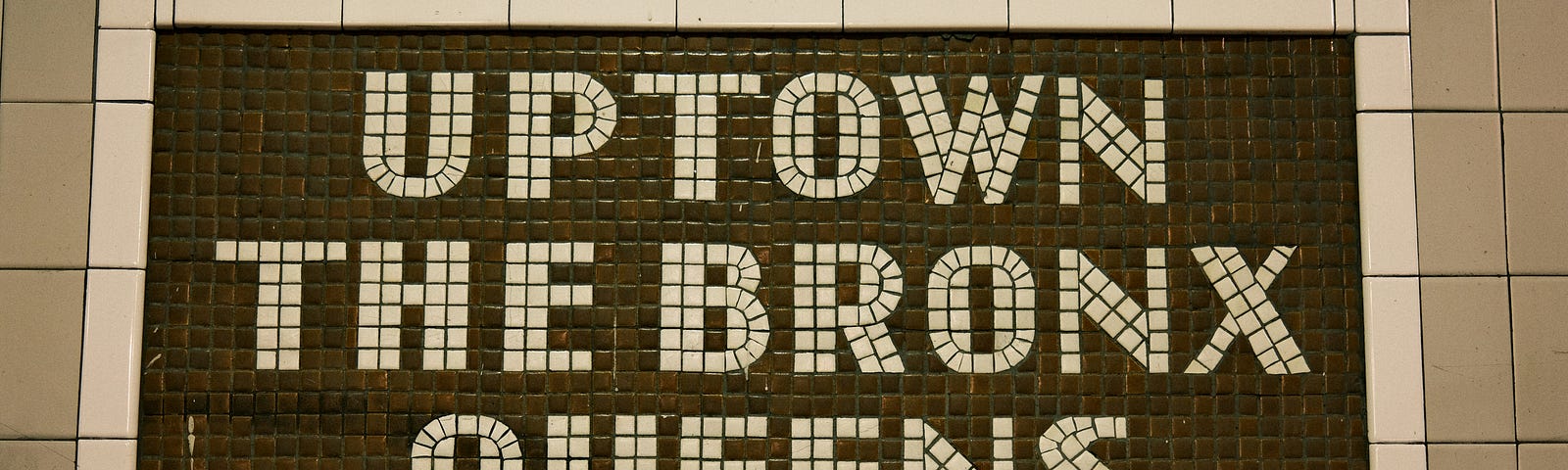 Huge wall subway sign that says Uptown, the Bronx, Queens — with a large arrow to the right.