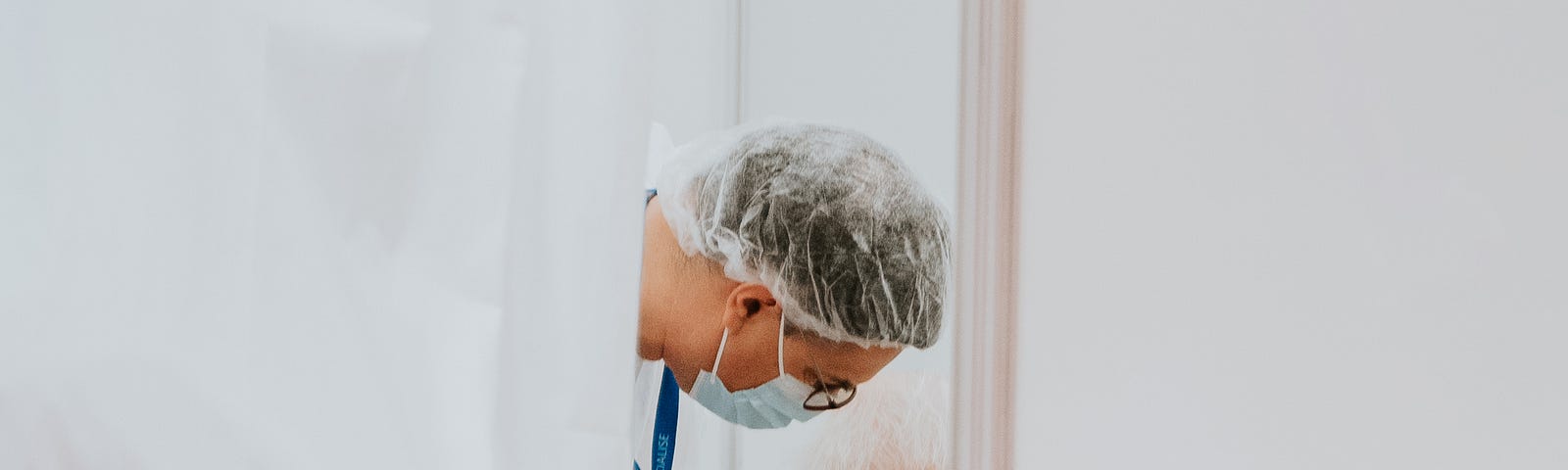 We peer through a door to see a doctor leaning over to administer a vaccine to an older individual.