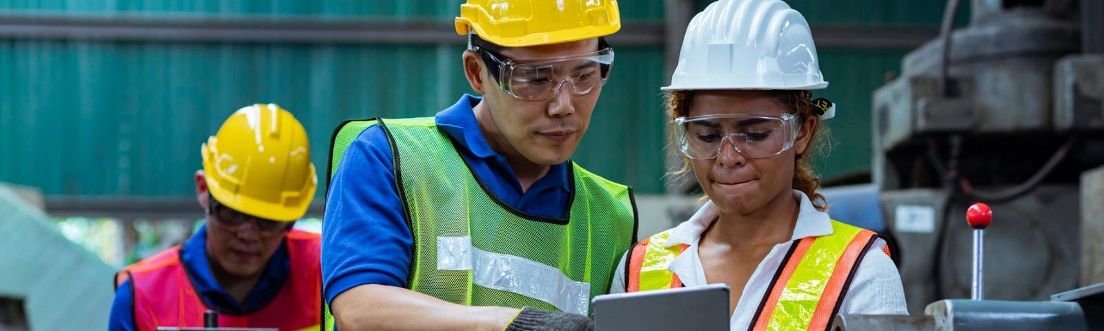 Two people review machine logs in a factory. Photo by Yozayo/Getty Images