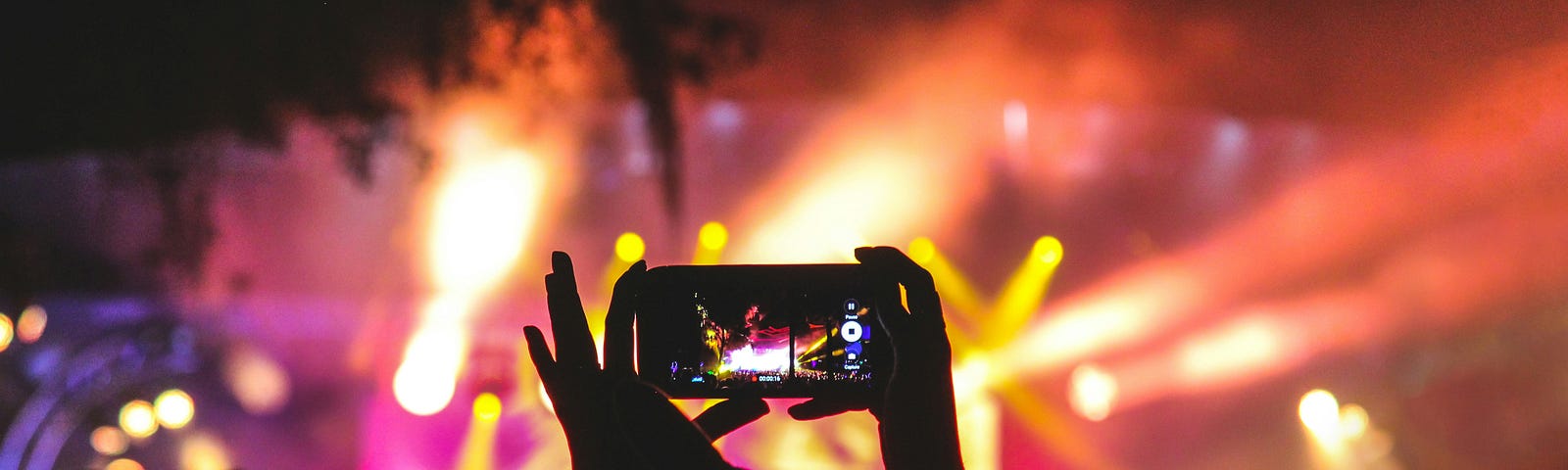 A person holding up a phone to record a concert