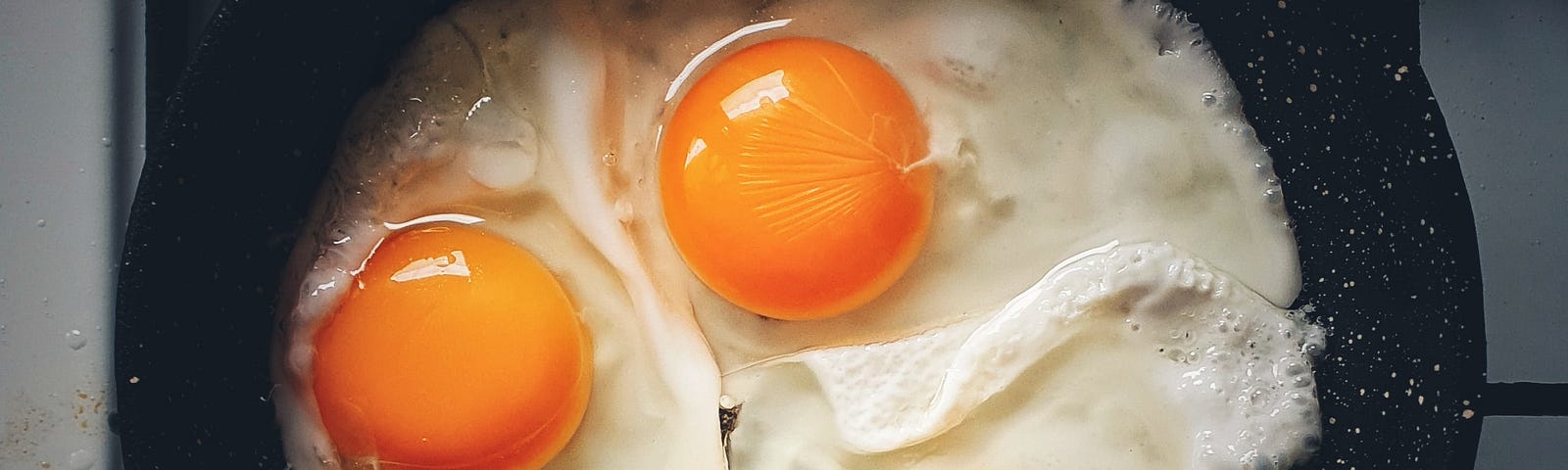 Three eggs frying in a pan