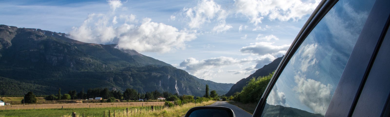 Scenic road trip with mountains, fields, and clear skies.