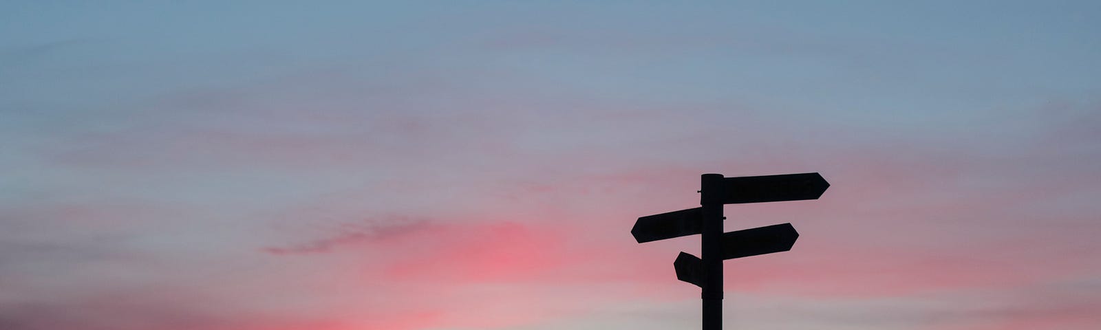 A signpost against a sunset sky