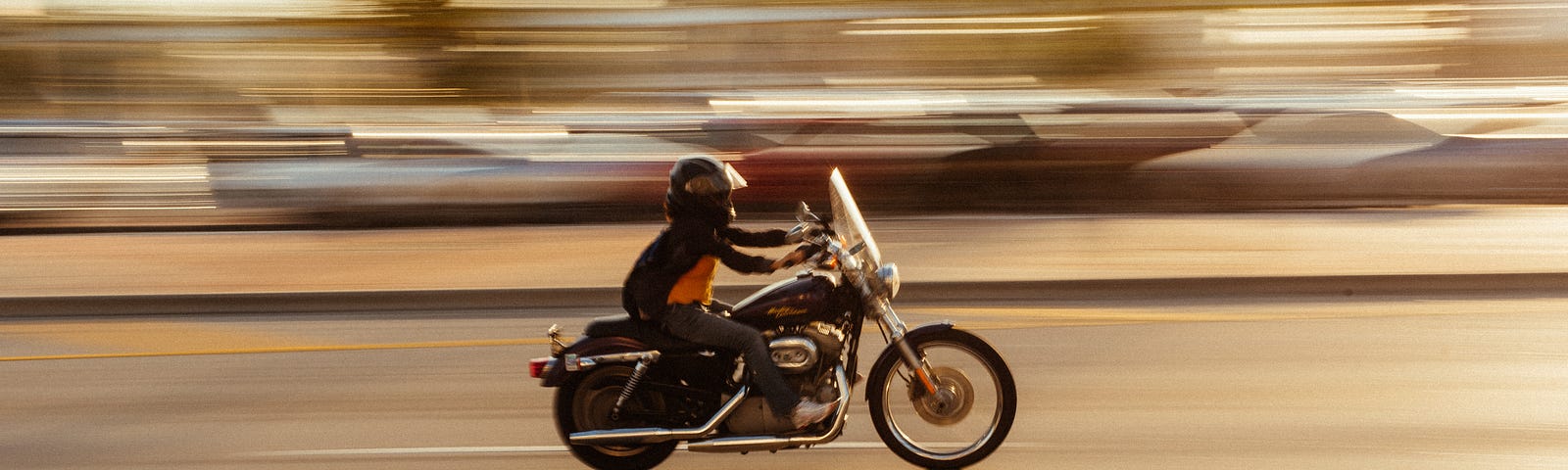 A person on a motorcycle with background blurred to show speed.