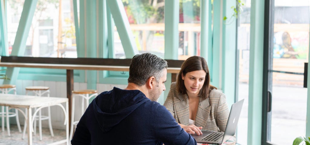 a lady and gentleman discussing something on a laptop