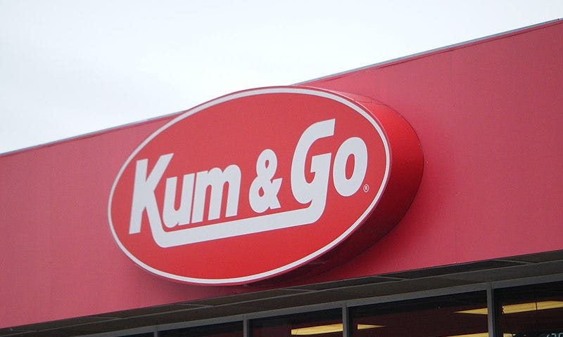 The logo for the gas station “Kum and Go,” which is white lettering on a red background