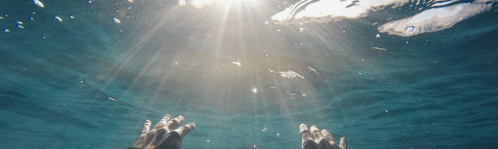 A man stretching his hands beneath the surface of water.