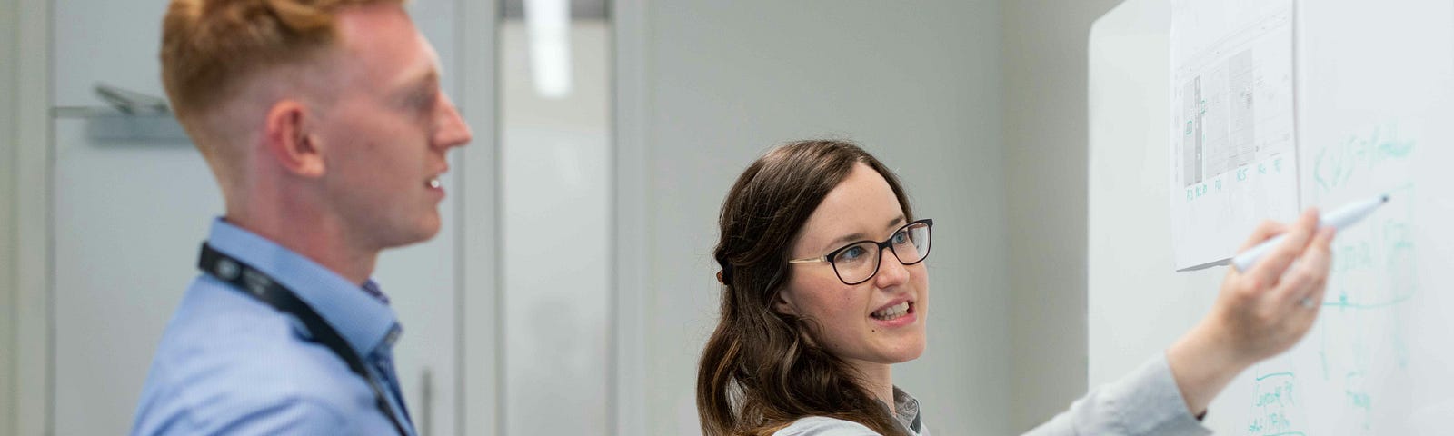 business meeting — people standing — looking at a whiteboard