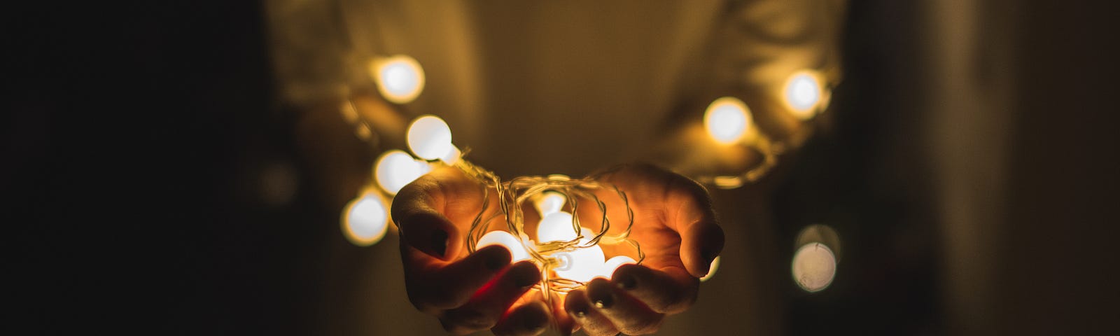 Woman wearing a white shirt and holding a string of white lights