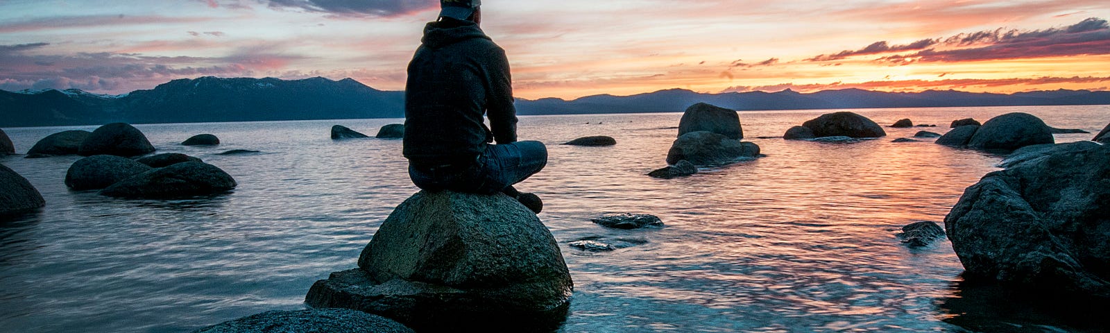 Men meditating on a rock in the water…