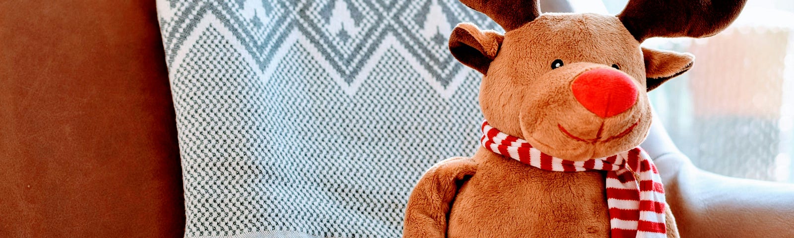 A stuffed Christmas reindeer sitting on a chair.