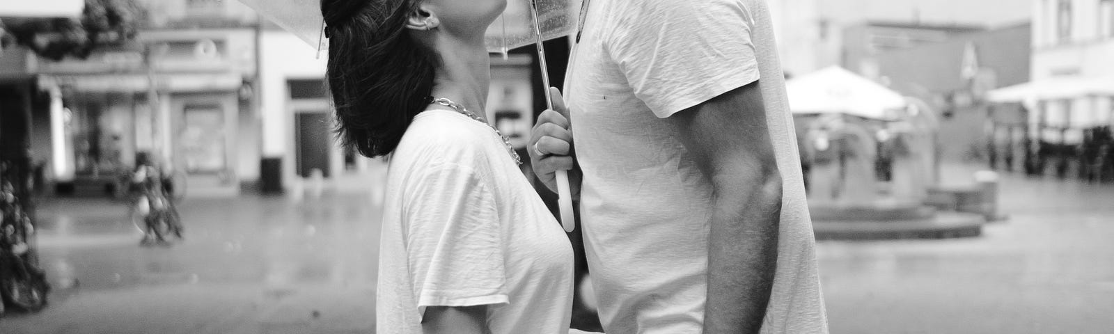 Man and woman outside kissing in the rain.