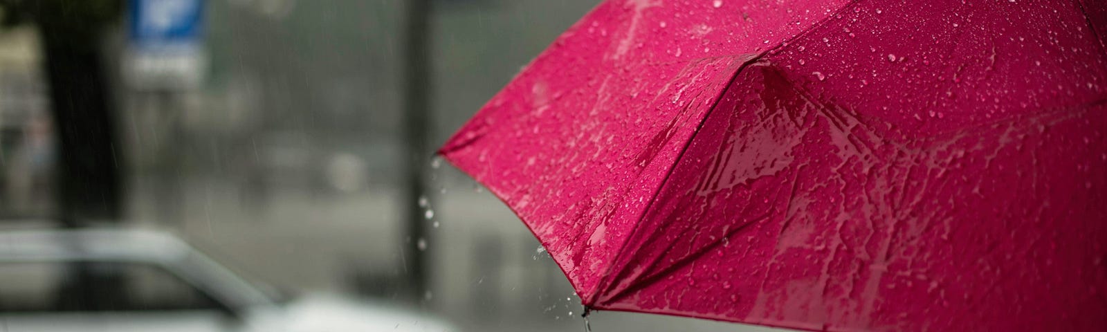 Crimson umbrella in a watery rainy street