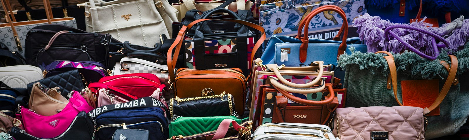 A crowded display of various designer handbags.