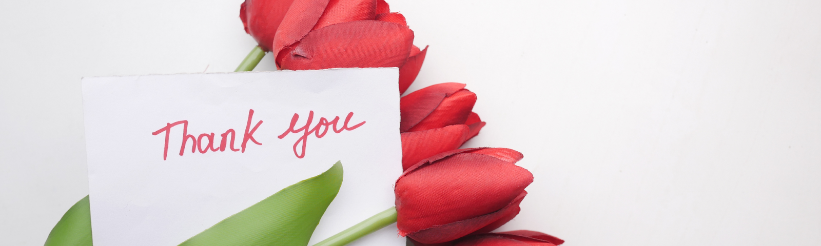 a bouquet of red roses with a thank you card