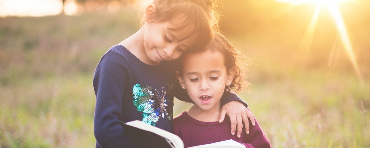 Two young girls reading the Bible.