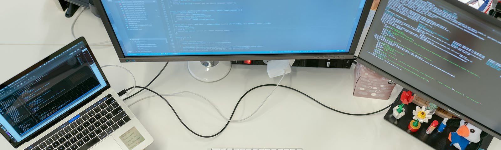 A programmer using 2 monitors and a laptop
