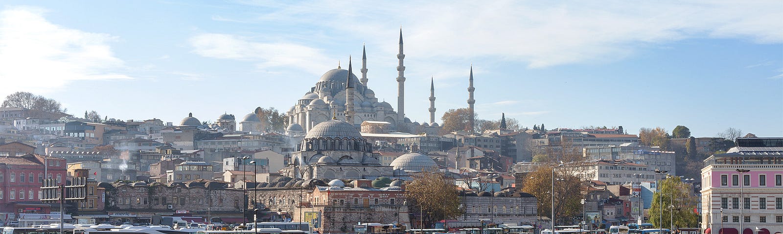 busy ferry terminal filled with colorful boats and a mosque looming in the background