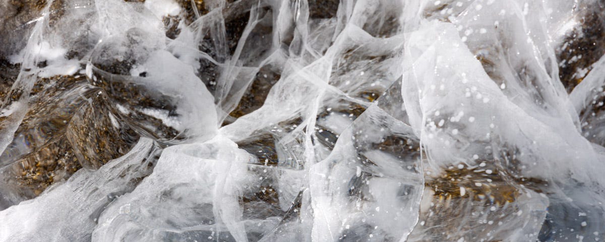 Lake ice that is cracked in intersecting diagonal lines.