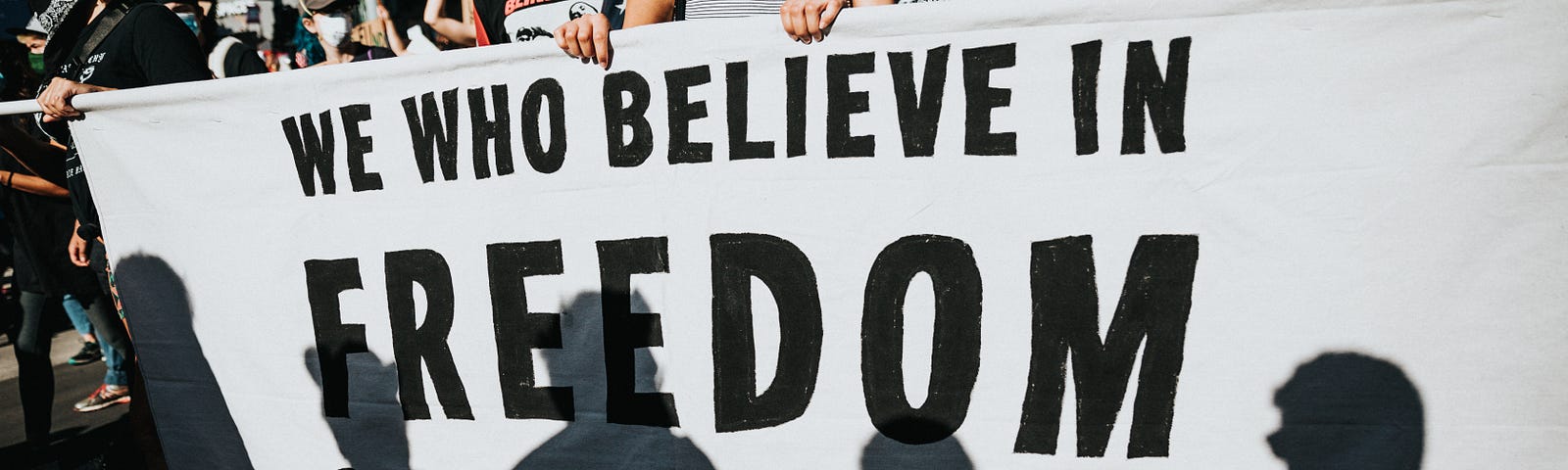 Protestors holding a sign that says, “We who believe in freedom cannot rest.”