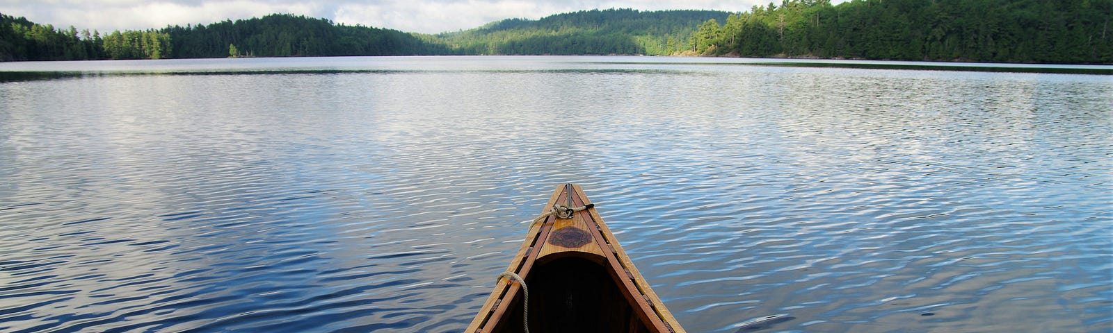 The front of a canoe on a peaceful lake