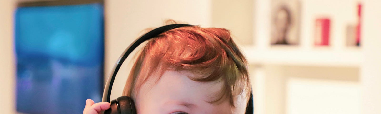 Small re-headed child listening on headphones
