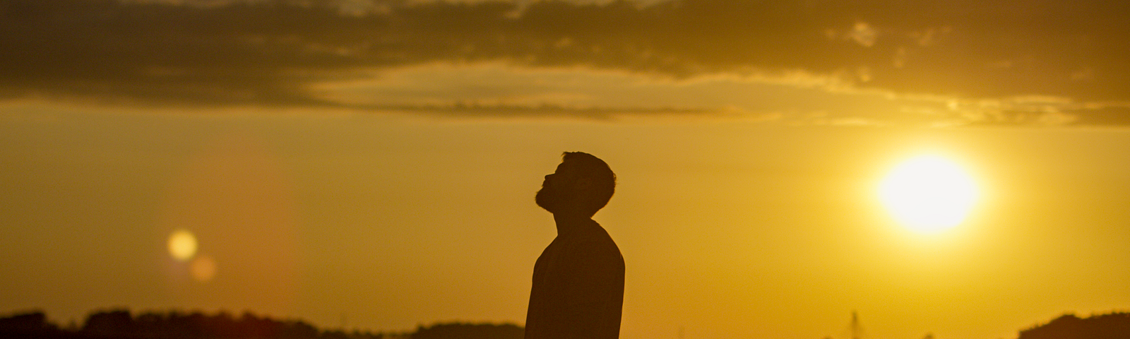 A man’s silhouette against the sunset, gazing upwards