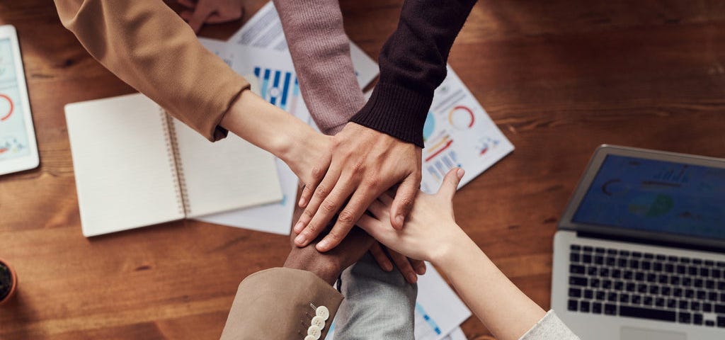 a team with hands together to signify team-work.