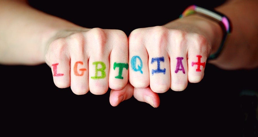 A pair of knuckled hands with the inscription, “LGBTQIA+”