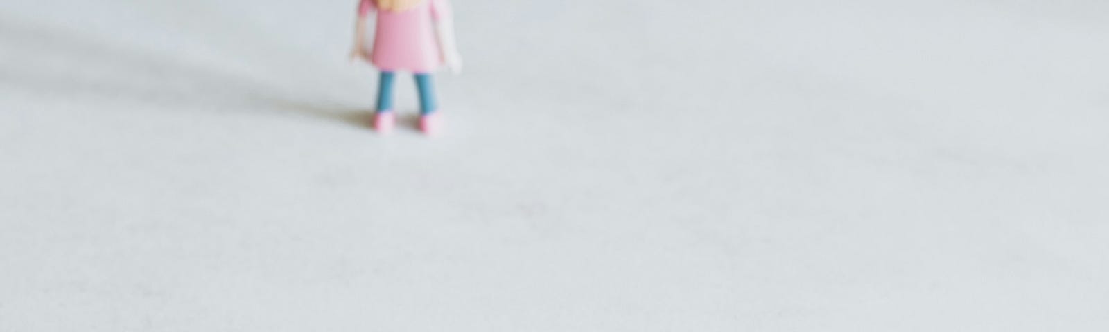 The image shows a figure of a girl facing away from the camera, with Scrabble tiles in the foreground spelling “LONELINESS.”