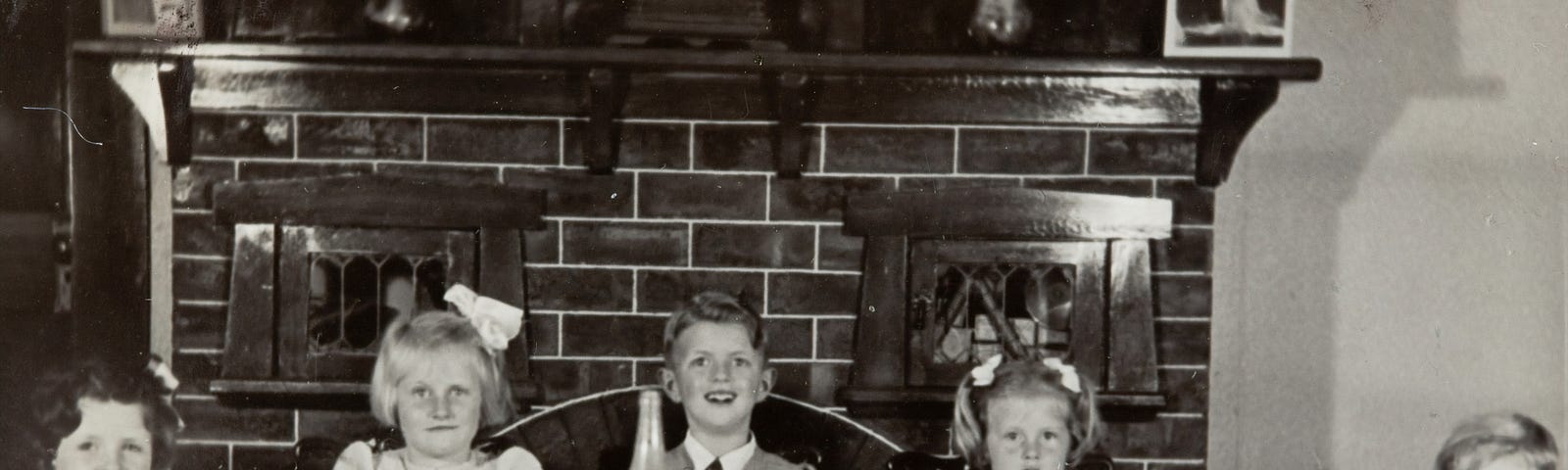 Sepia photo of siblings sitting around a table as children.