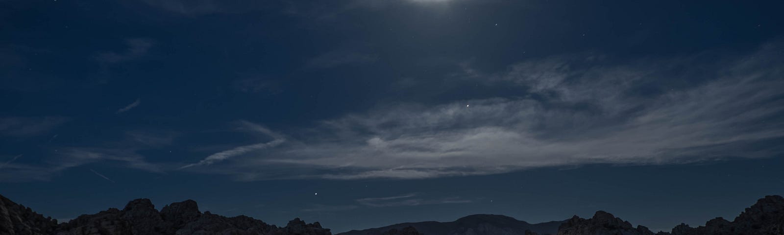 A train moving through the landscape at night, under a moon