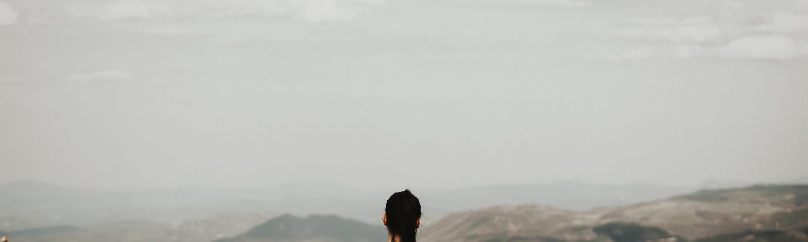 A woman sitting alone in the mountains.