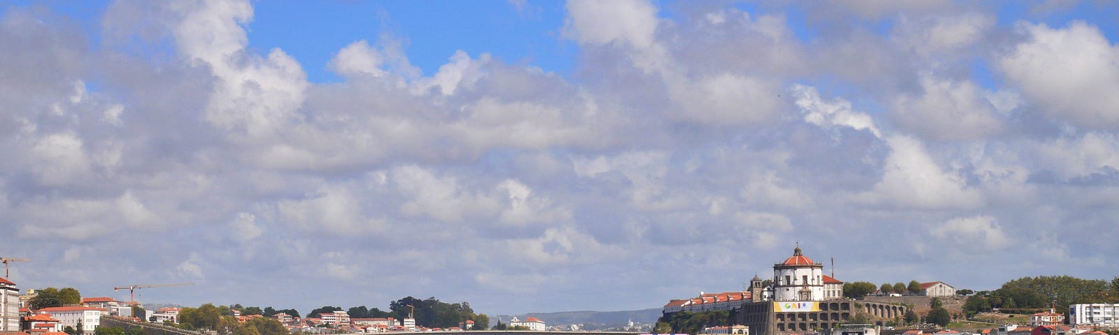 Someplace in Portugal, with a bridge, beautiful terra cotta roofs, and fluffy clouds