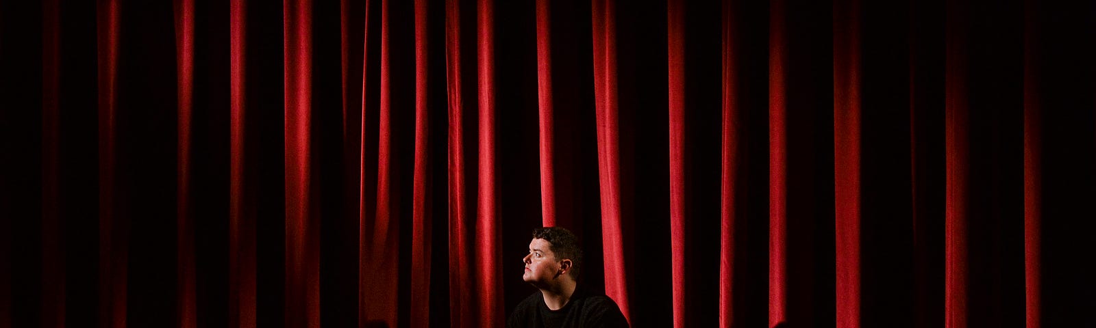 Actor in front of red curtains