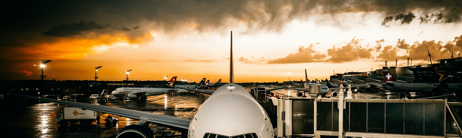 A plane waits on the tarmac of the airport during sunset time.