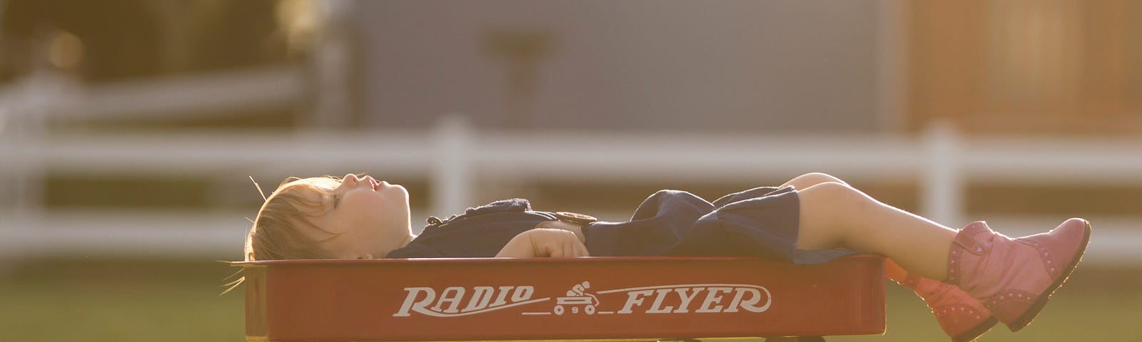 A child relaxing on a Radio Flyer cart during summer